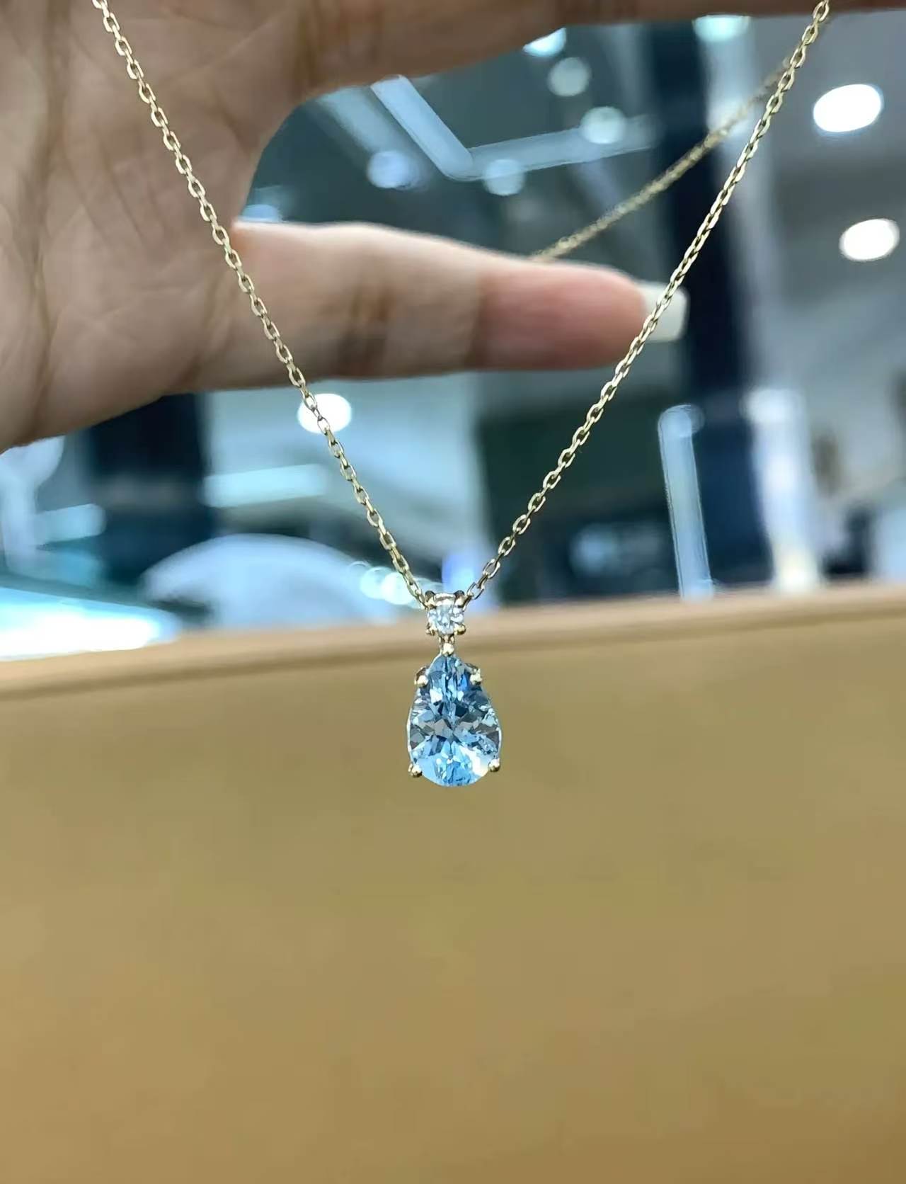 Gold chain pendant with a pale blue teardrop stone