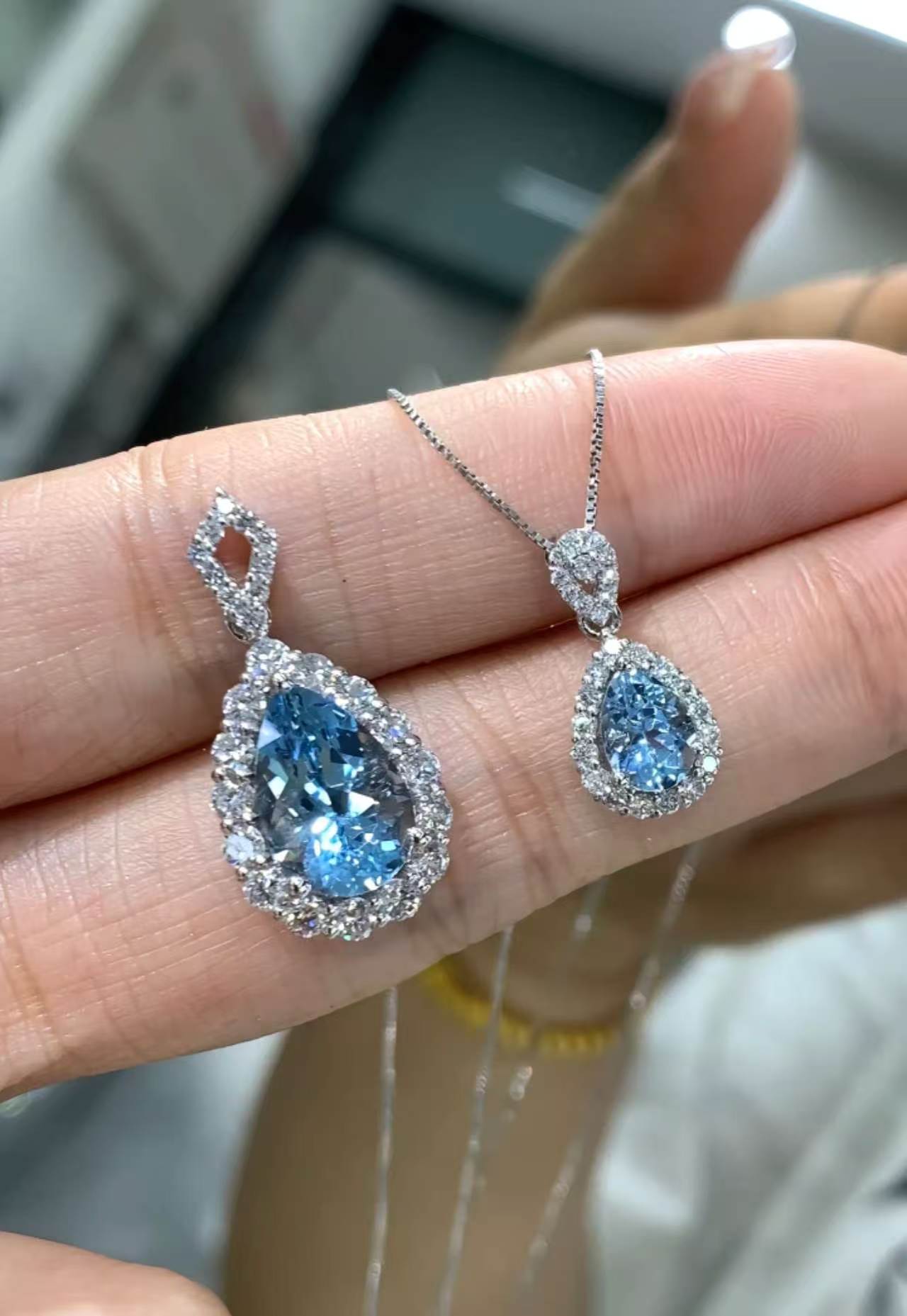 Cascade pear-cut halo earring beside the matching pendant